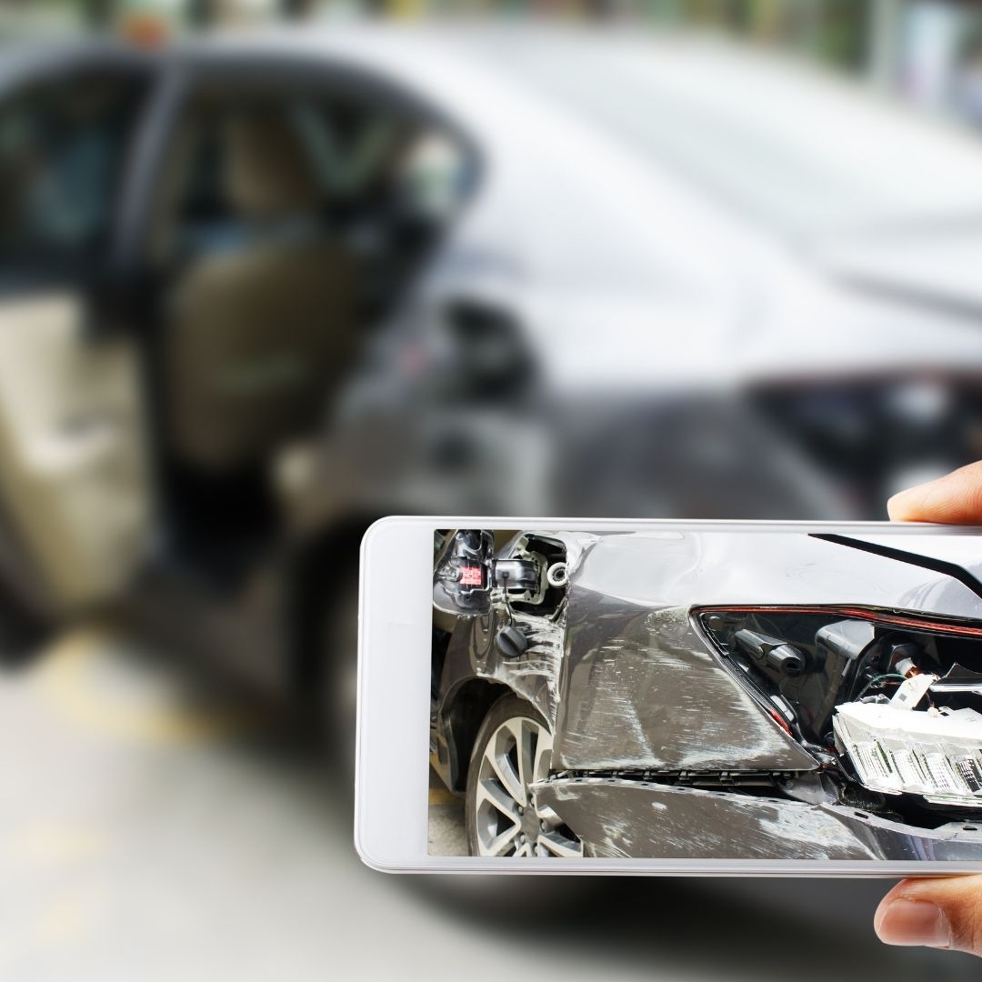 A person taking a picture of a car accident on their smartphone.