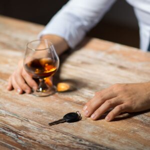 peson en una mesa con una bebida alcohólica y llaves de auto