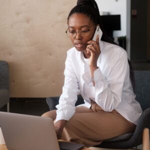 a woman on a phone call while looking at a laptop