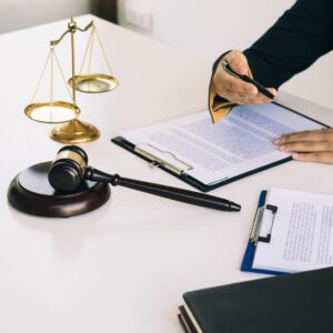 people looking at paperwork in front of a gavel and the scales of justice