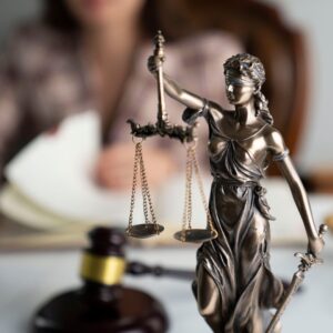 a lady of justice statue with a gavel in the background