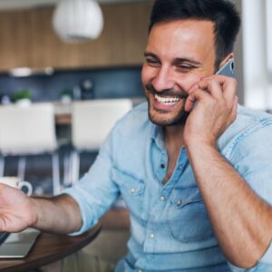 a man smiling and talking on a cellphone
