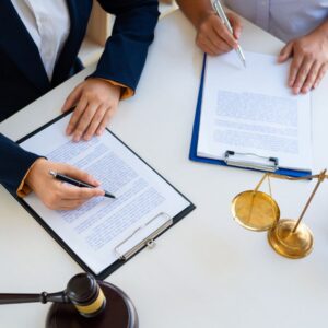 two people looking at paperwork in front of a gavel and the scales of justice