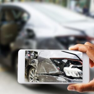 una persona tomando una foto del daño de un accidente automovilístico con un teléfono inteligente