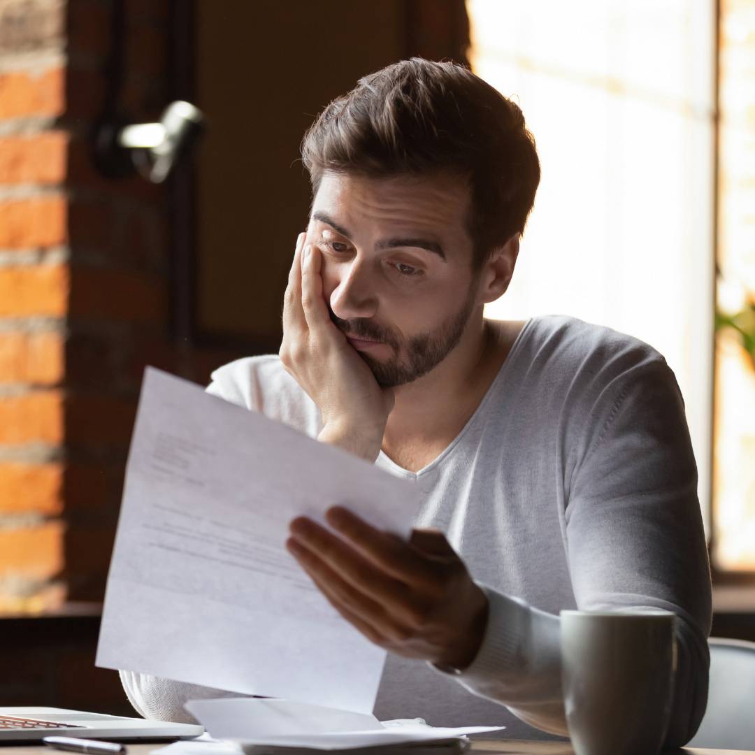 A young man looking confused while looking at paperwork