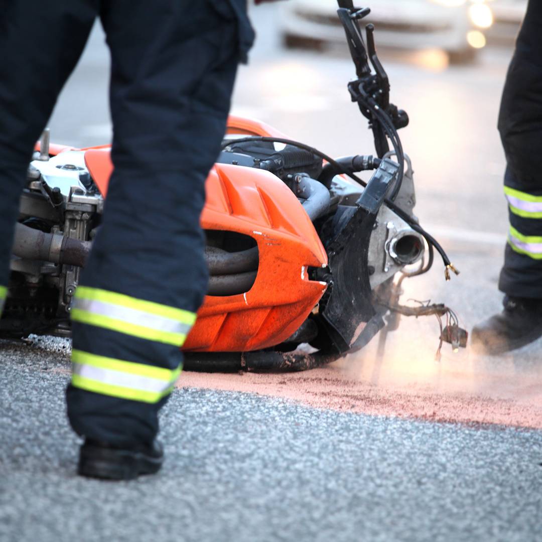 Two firefighters standing by a wrecked motorcycle