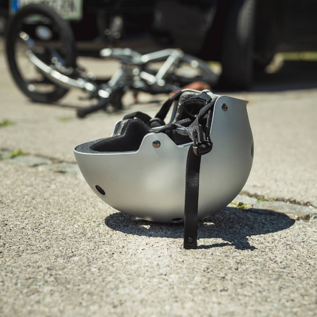 A wrecked bike and bike helmet on the road after an accident with a car