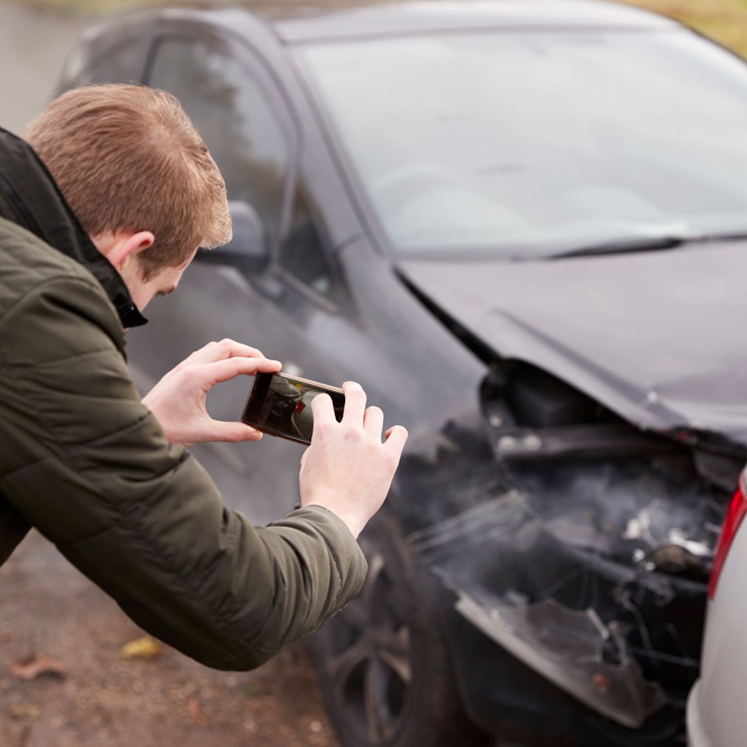 man taking picture of car crash