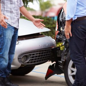 Two men at the scene of a car accident looking animated.