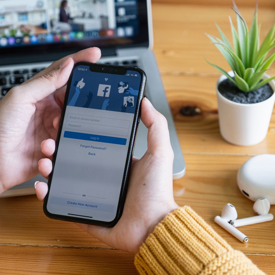 Person holding a phone with the Facebook login on the screen.