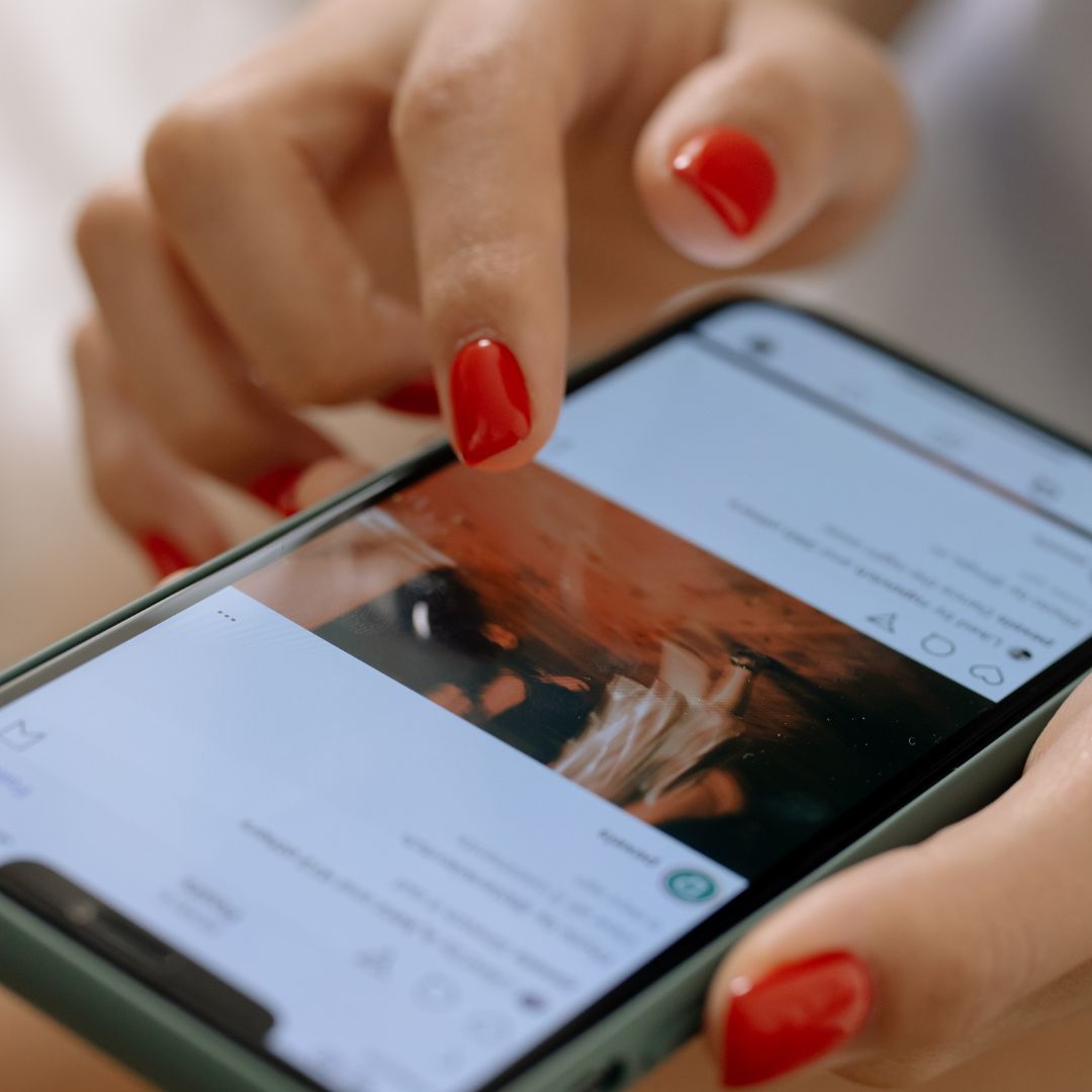 Woman with red fingernails scrolling through social media. 