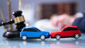 Red and blue toy cars colliding in front of a gavel.