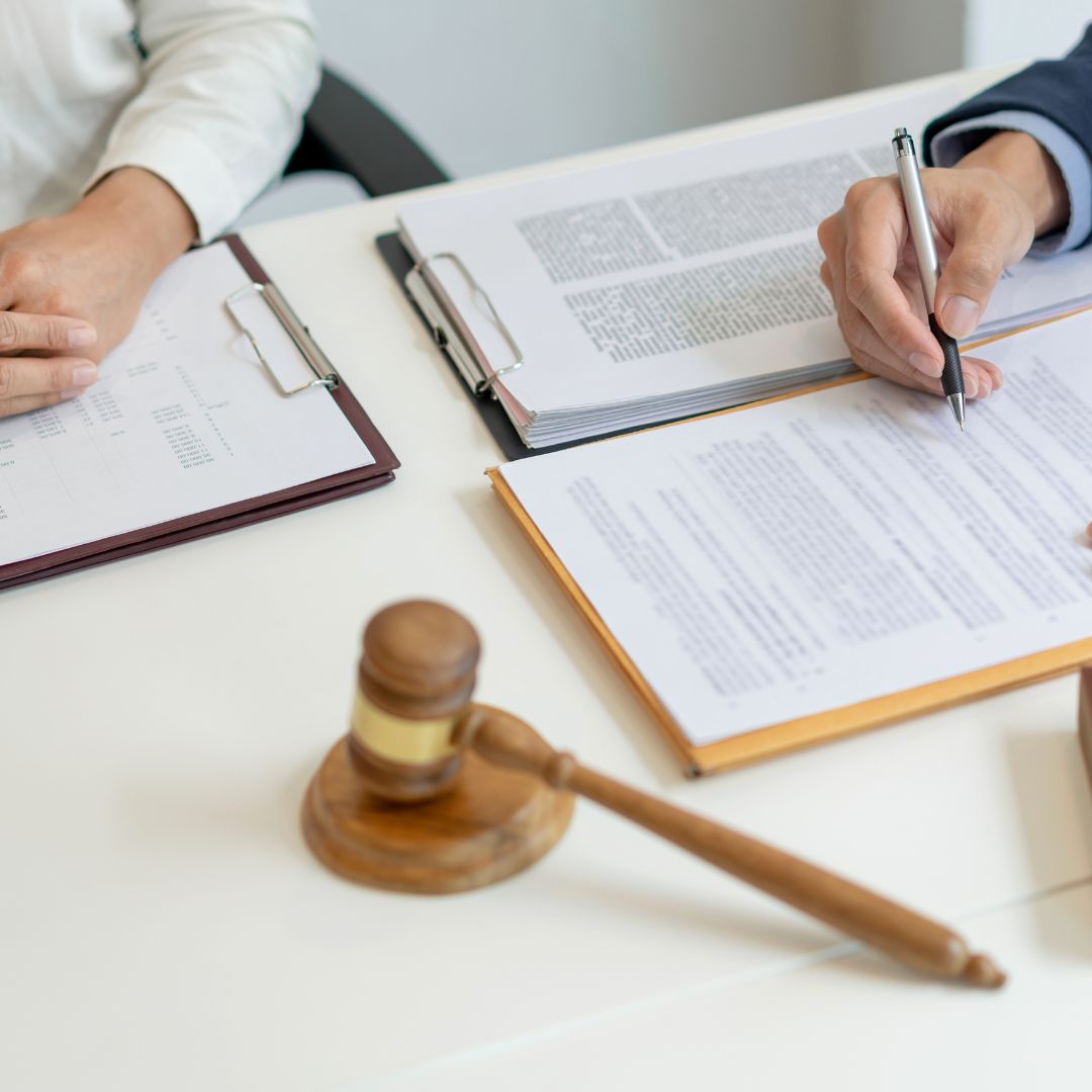 Two people looking over documents with a judge gavel in the middle
