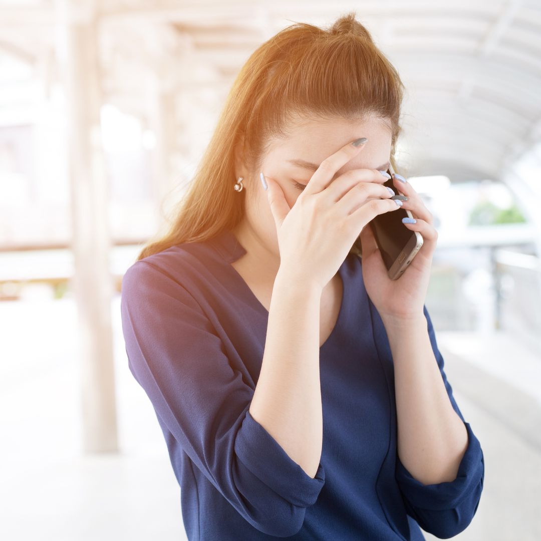 Women speaking on the phone and grabbing her head in stress