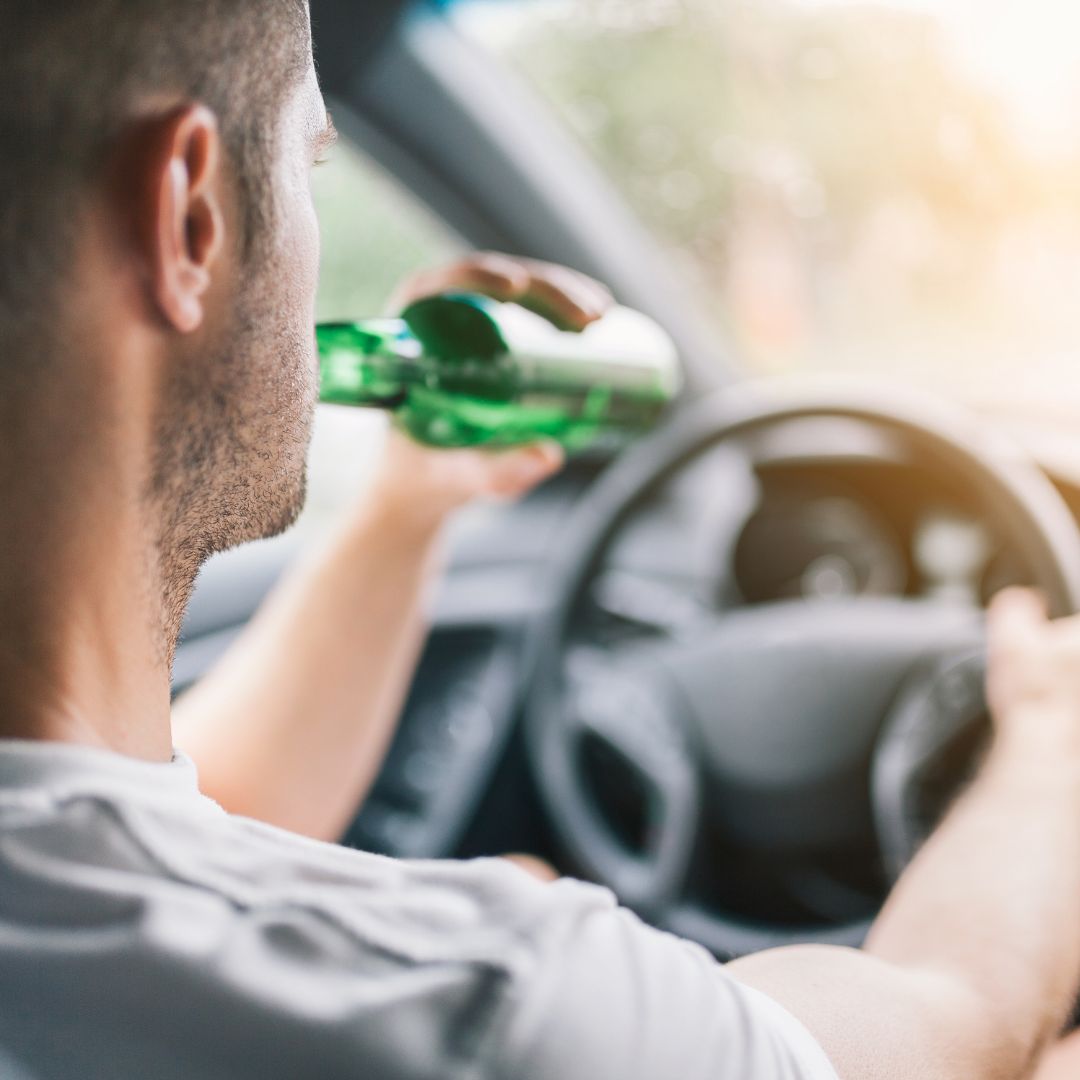 A man drinking a beer while driving