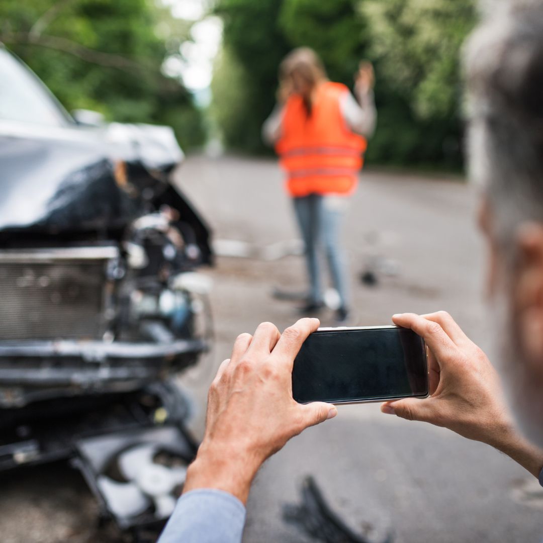 Man taking a picture of a car crash