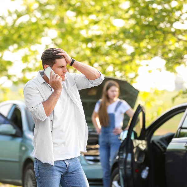 Un hombre al teléfono tras un accidente de coche con una mujer
