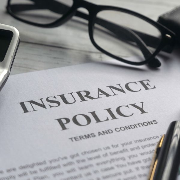 A pair of glasses next to a document that says Insurance Policy