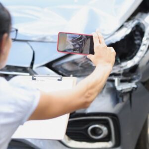 A women taking a photo of her damaged car after a crash