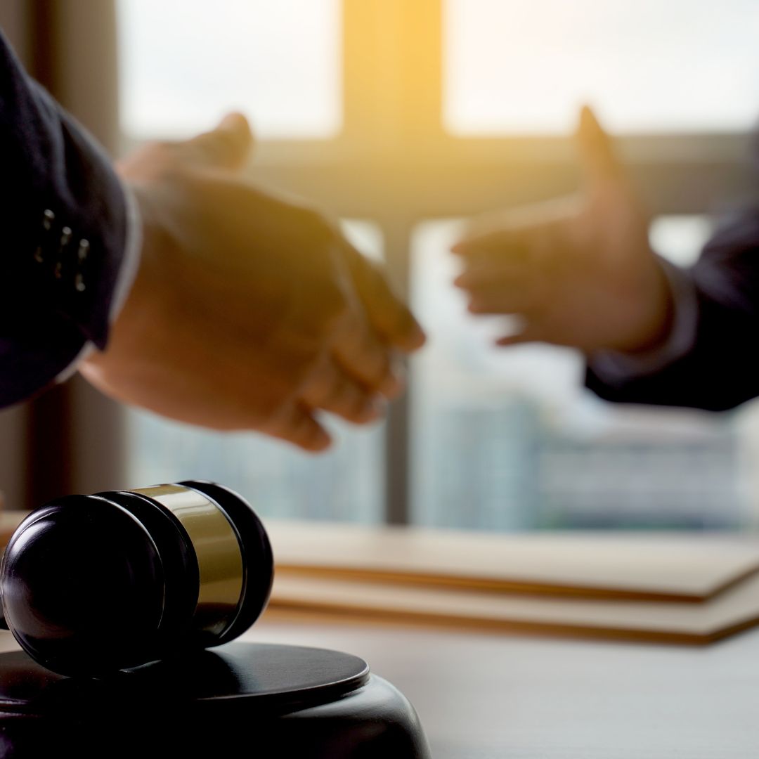 handshake in legal office with a gavel on the desk