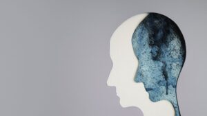 A white figure of a head right next to a blue figure of a head to represent sadness