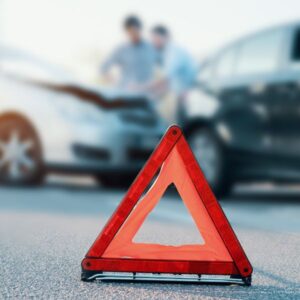 A caution sign with a car crash in the background