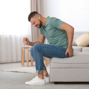 un hombre sujetándose la zona de los glúteos por el dolor
