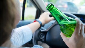 Una persona que conduce mientras bebe cerveza
