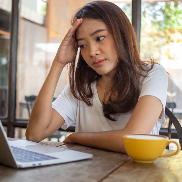A women grabbing her head while looking at her laptop