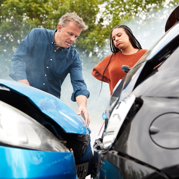 Two people looking at the aftermath of a car crash