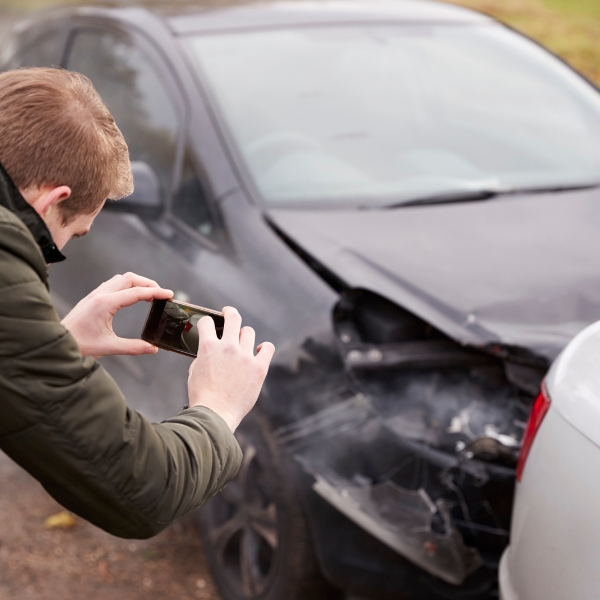A man taking a photo of a car crash