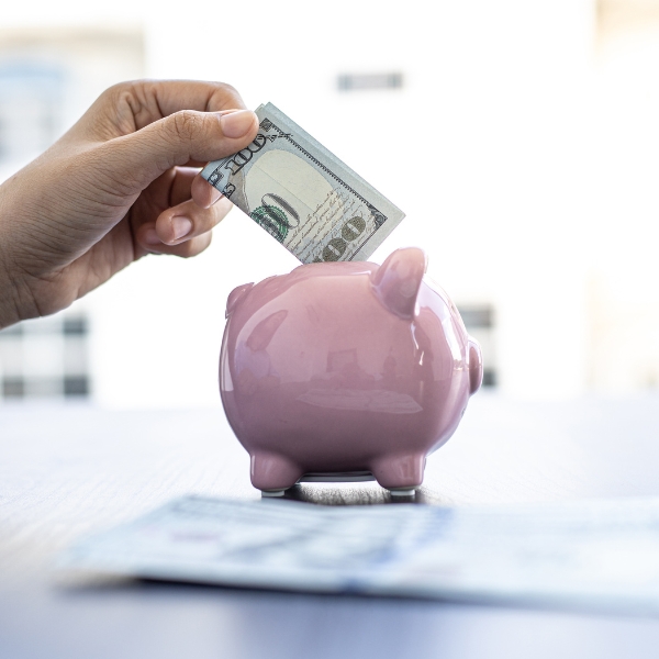 Someone placing money into a piggy bank