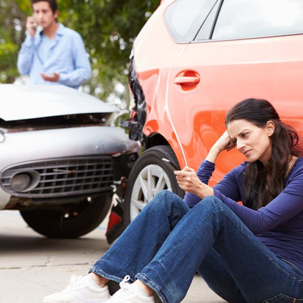 Una mujer sentada junto a su coche tras un accidente
