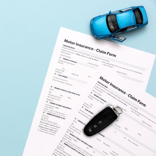 A car insurance claim form next to a toy car and car keys