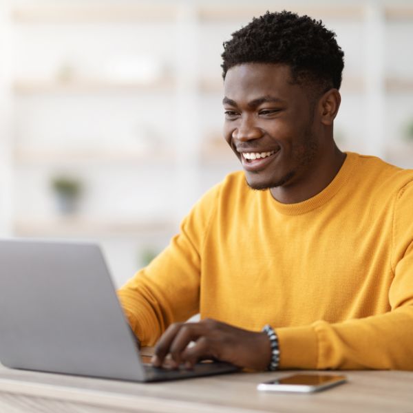 A smiling man on a laptop