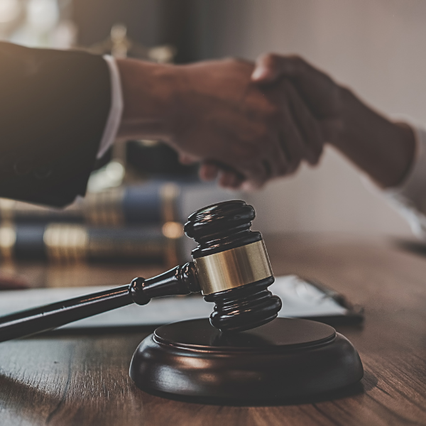 A judge gavel and people shaking hands