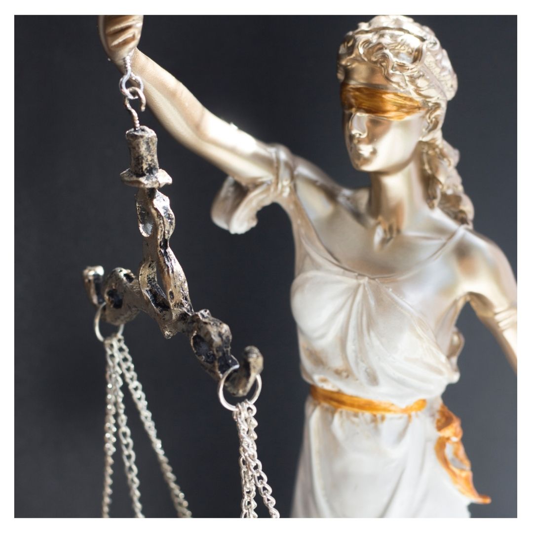 Una estatua blanca y dorada de la dama de la justicia