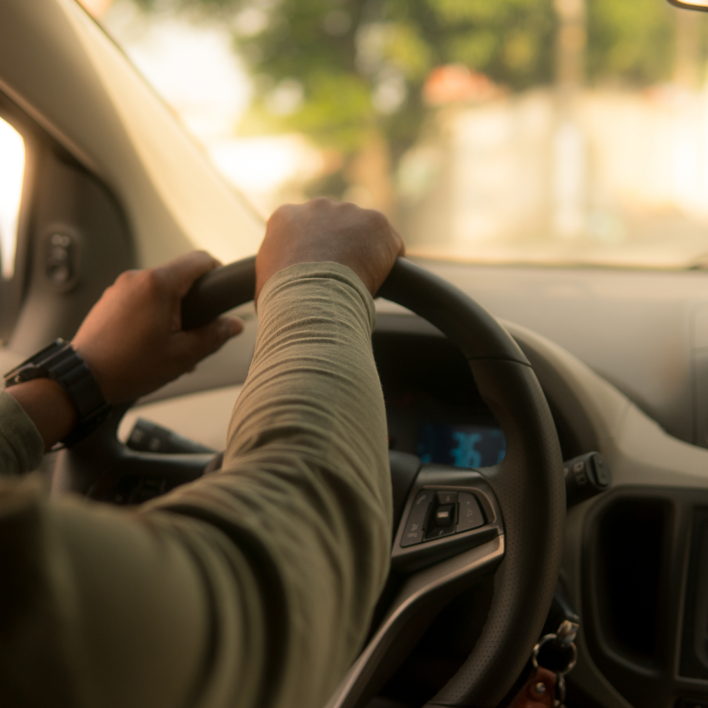 A person with their hands on a steering wheel