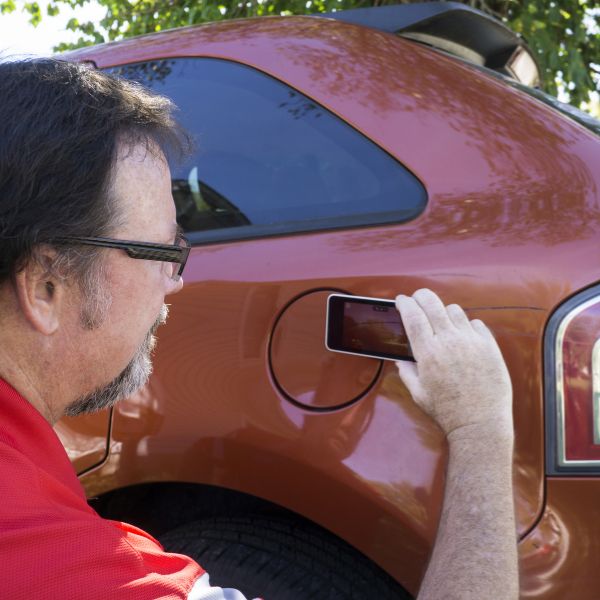 A man taking a picture of his vehicle
