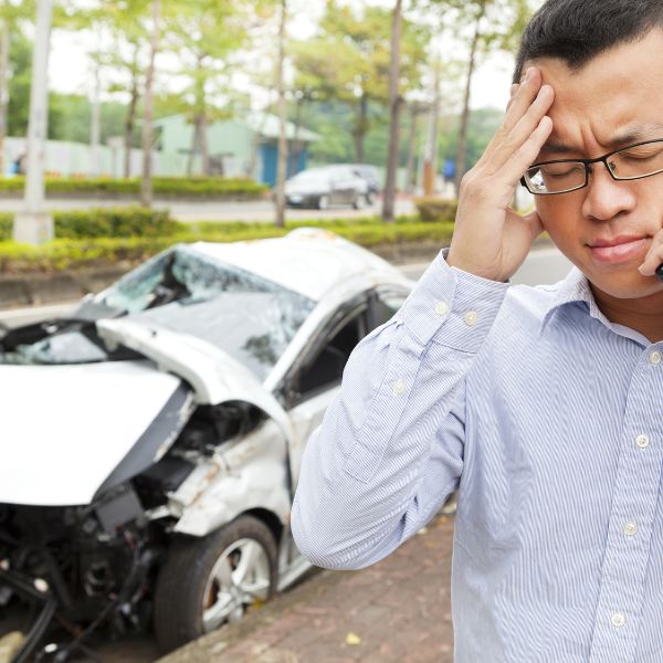 Man grabbing his head and on the phone after a crash