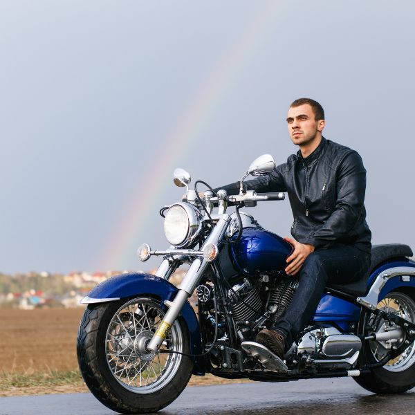 A man in a leather jacket riding a motorcycle