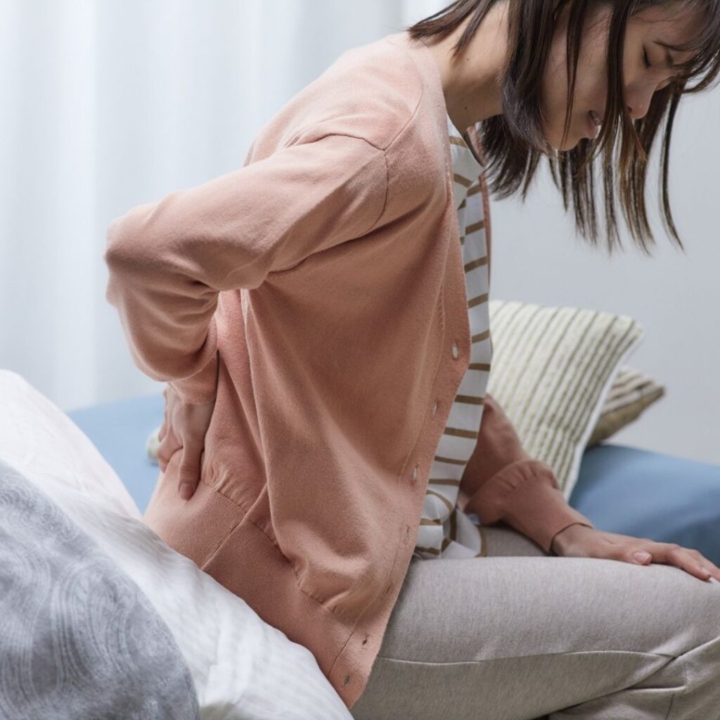 Una mujer agarrándose la espalda con dolor