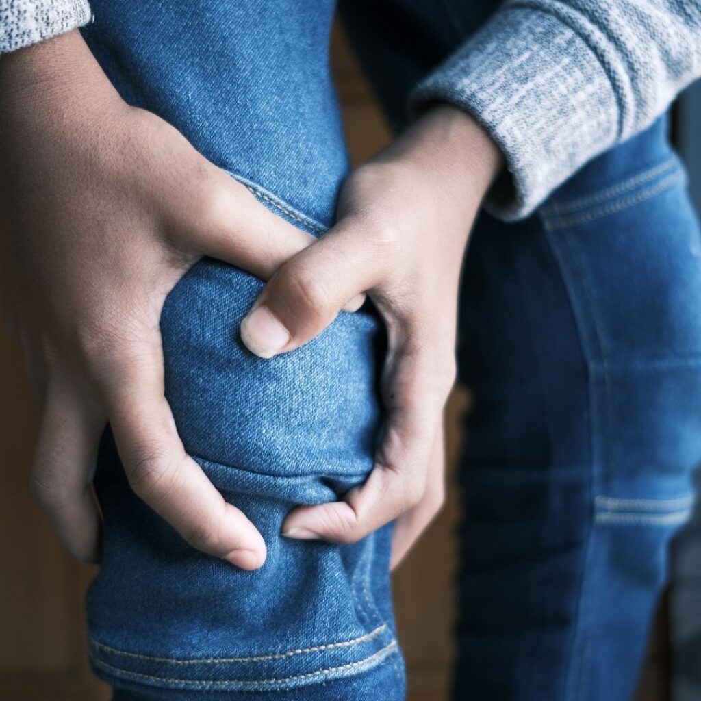 Person grabbing their knee in pain