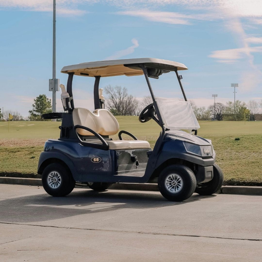 Dark blue golf cart parked outdoors on a paved surface.