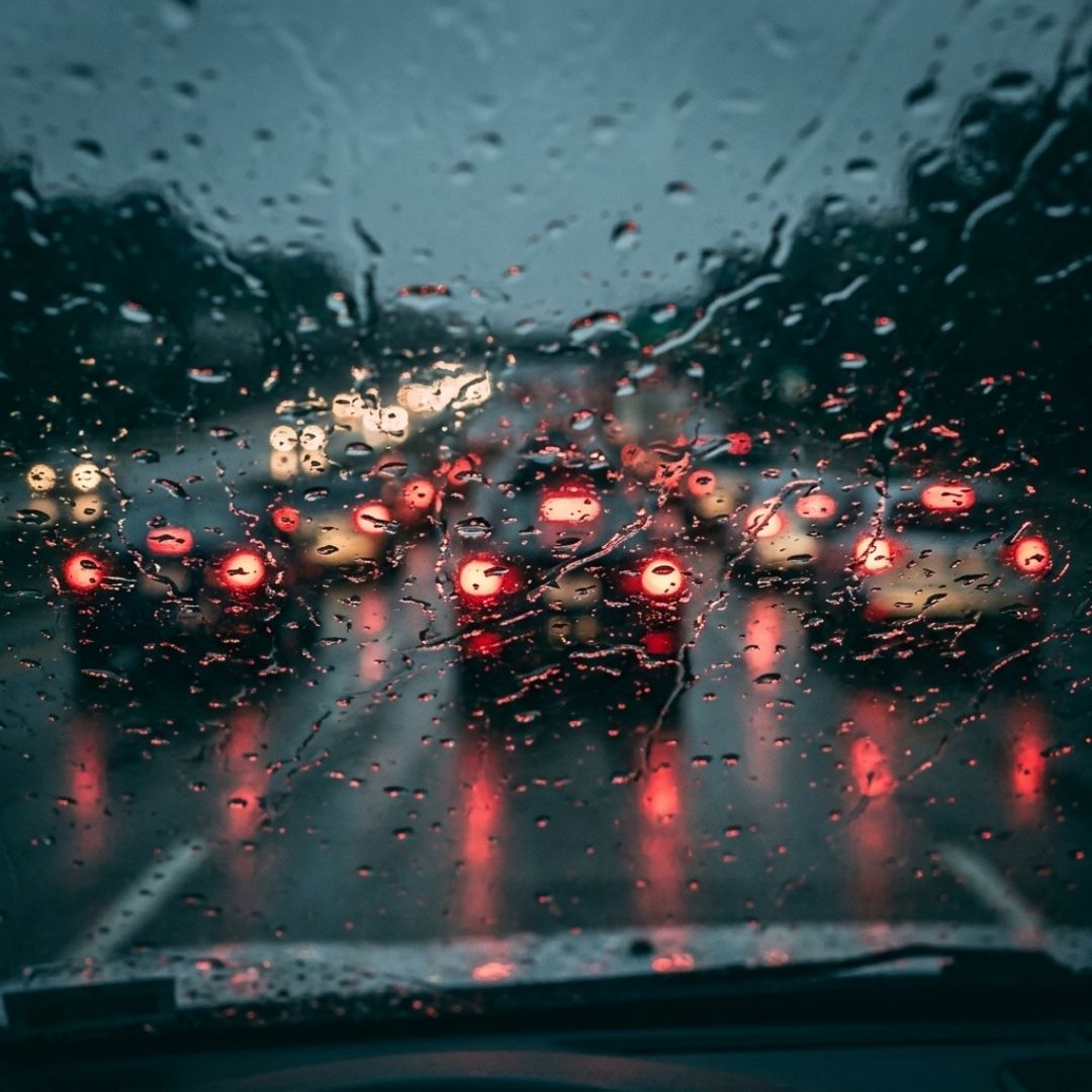 Driver view through a rain-drenched windshield with active wipers during a storm.